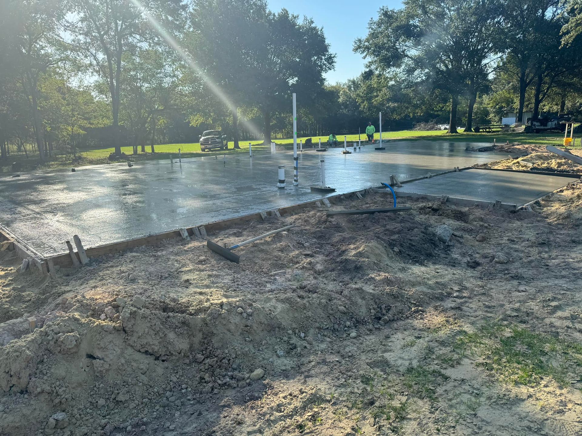 A concrete floor is being built in a yard with trees in the background.