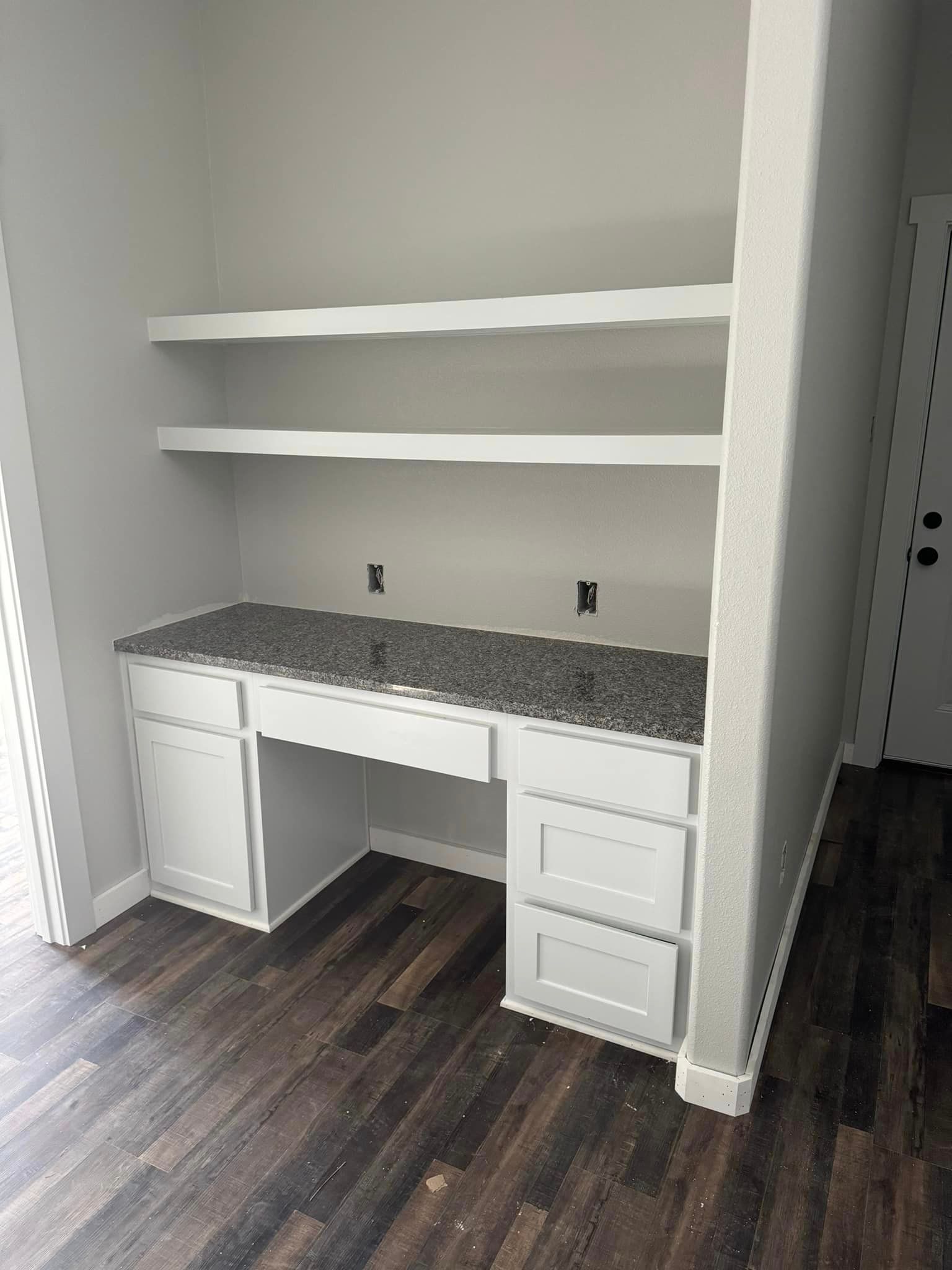 A room with a desk and shelves in it.