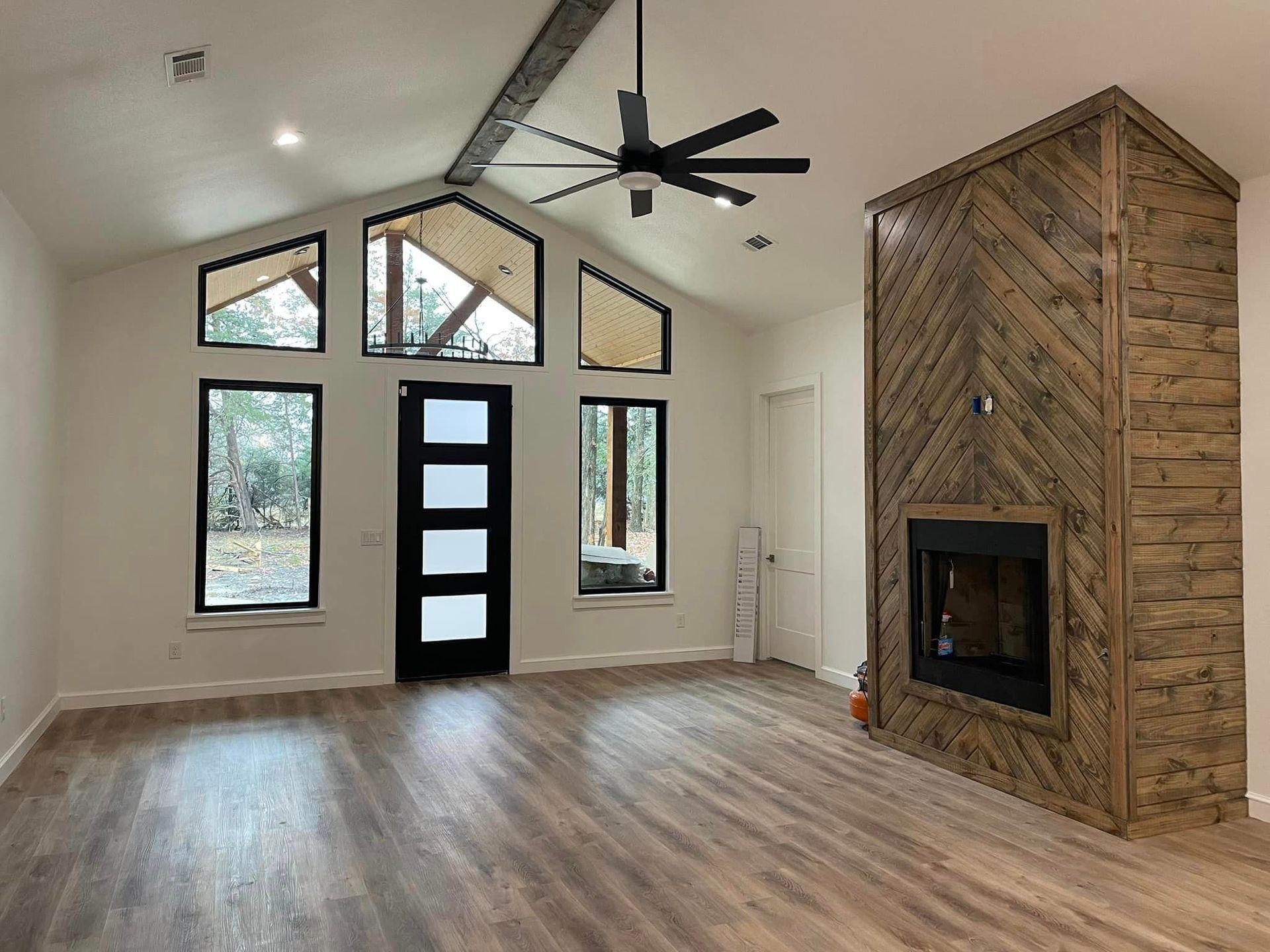 An empty living room with a fireplace and a ceiling fan.