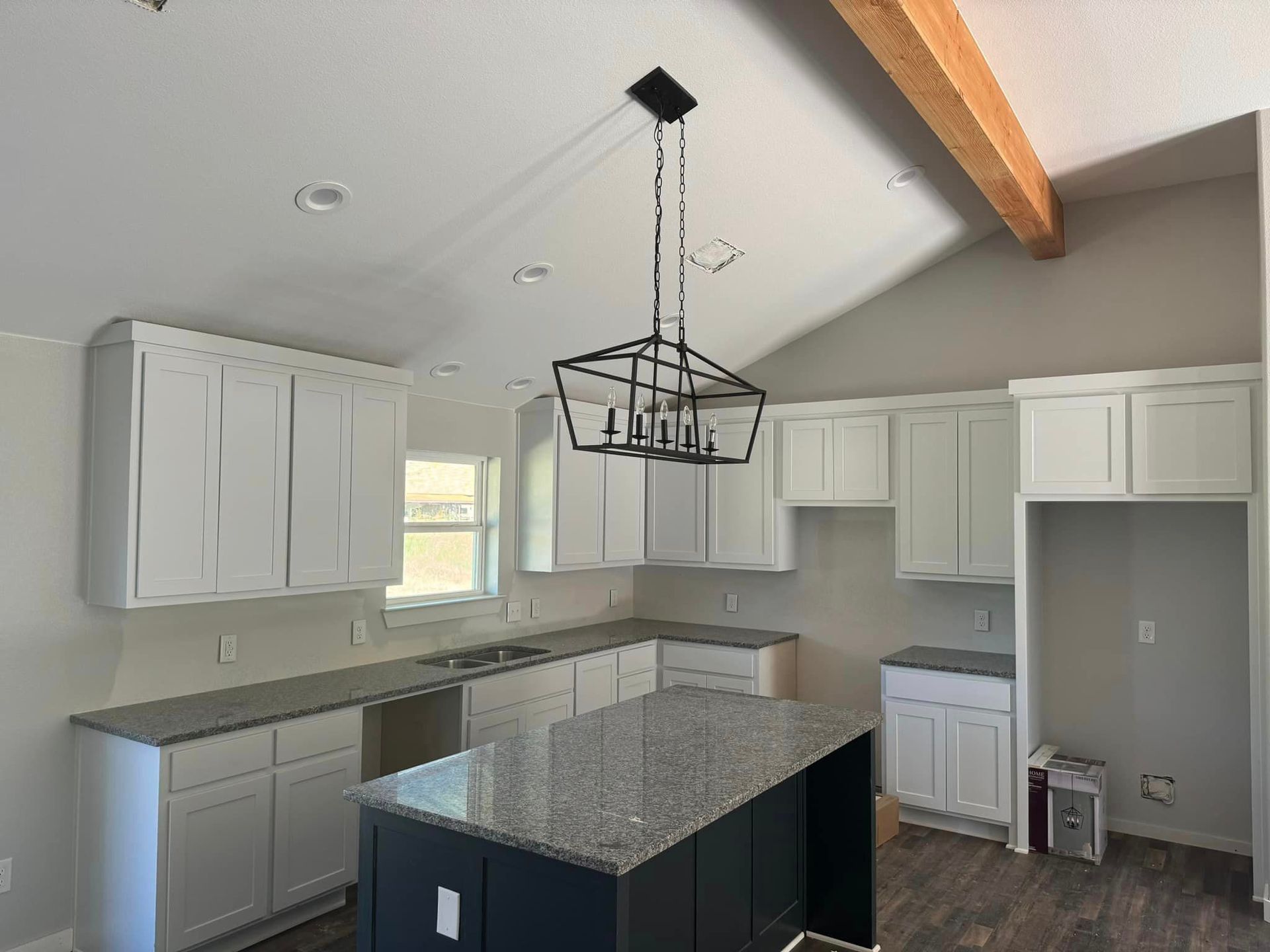 A kitchen with white cabinets , granite counter tops , and a large island.