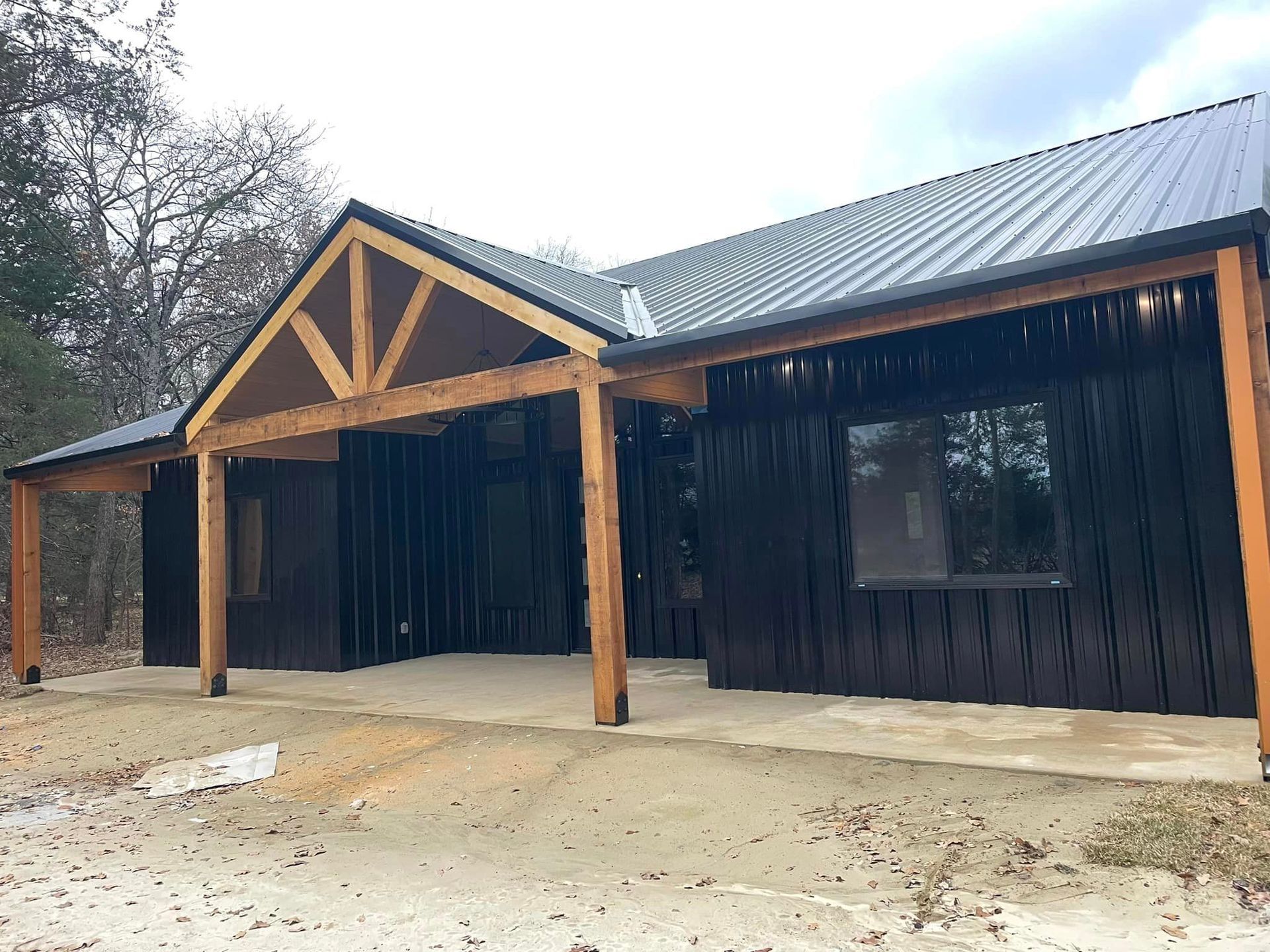 A large black house with a wooden porch and a metal roof.