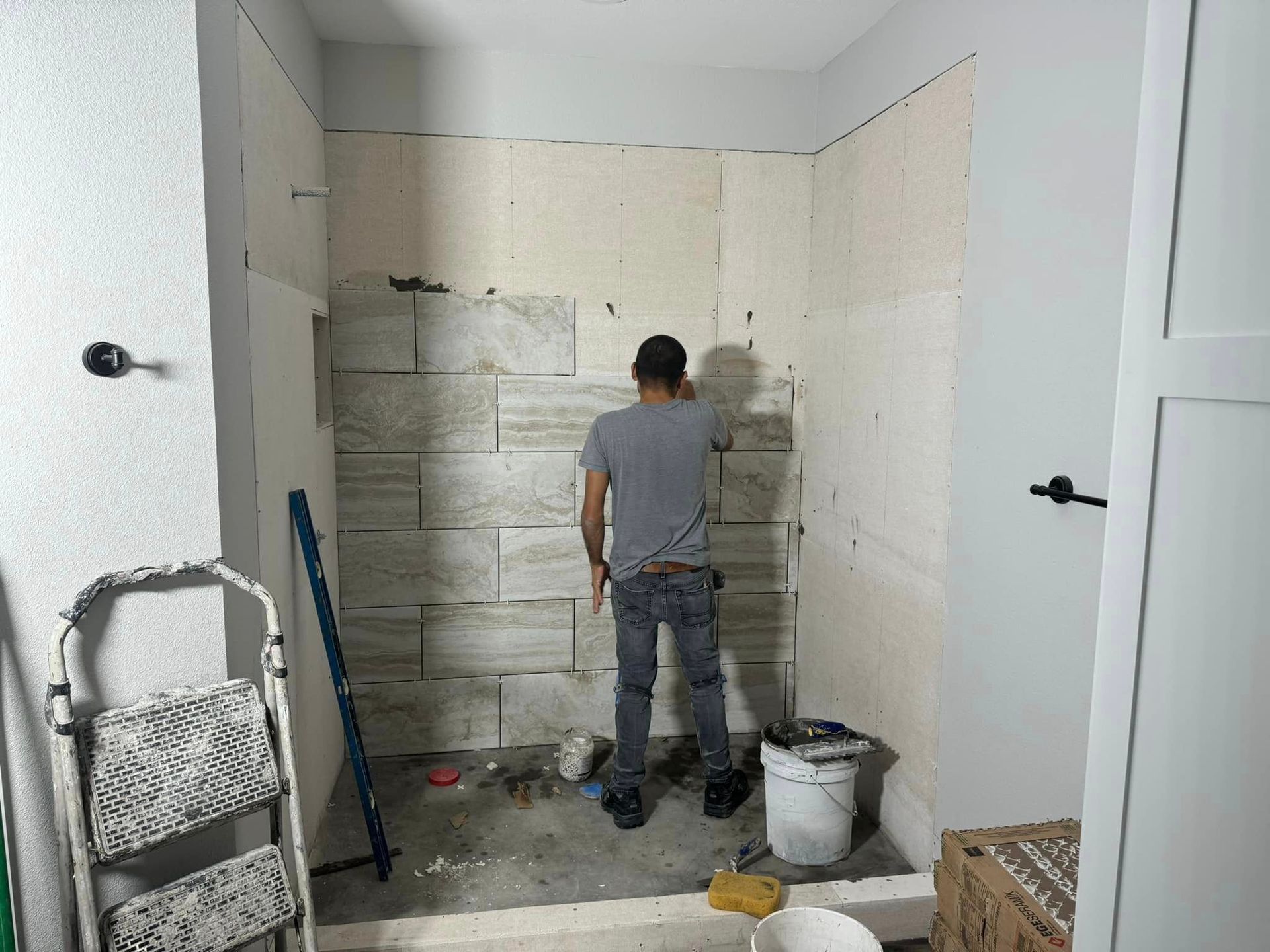 A man is working on a wall in a bathroom.