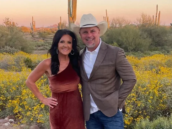 A man and a woman are posing for a picture in front of a field of flowers.