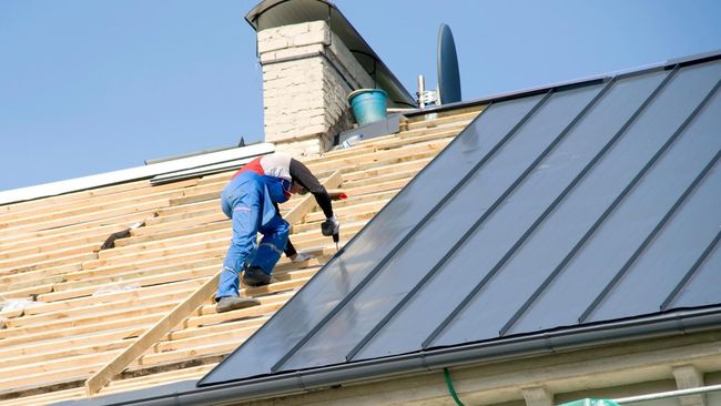 A man is working on the roof of a house.