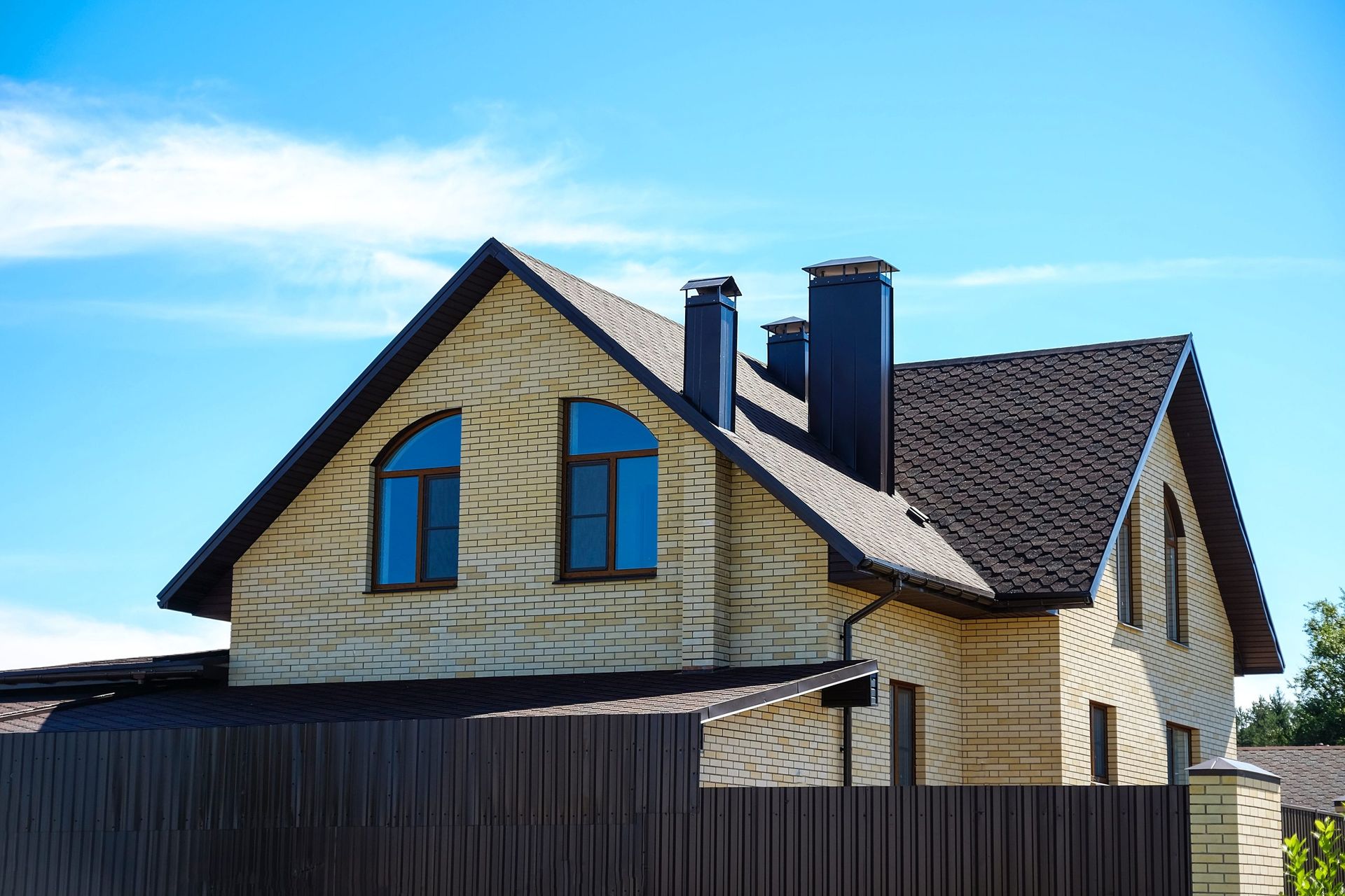 A large brick house with a wooden fence in front of it.