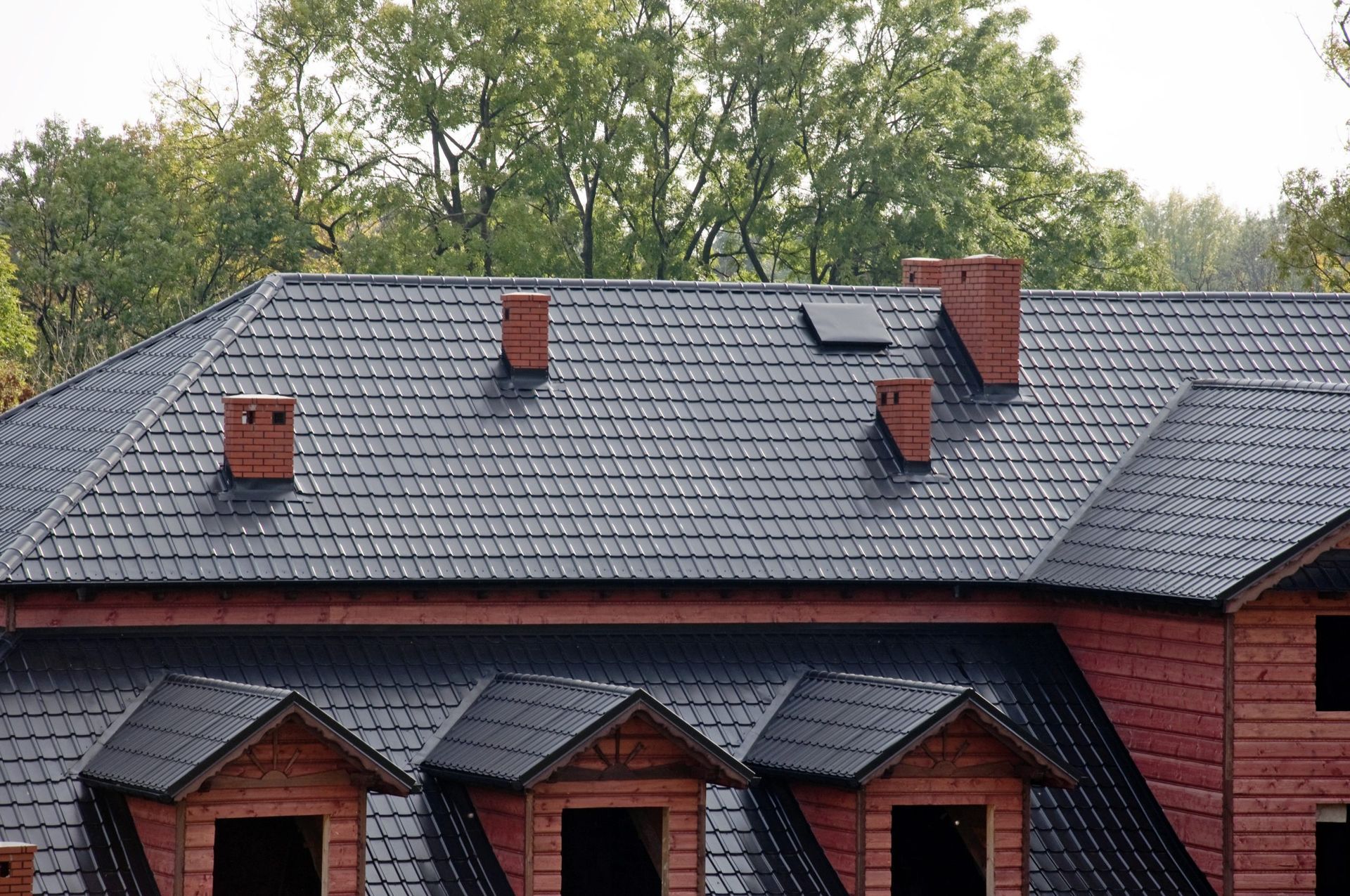 A brick house with a black roof and chimneys