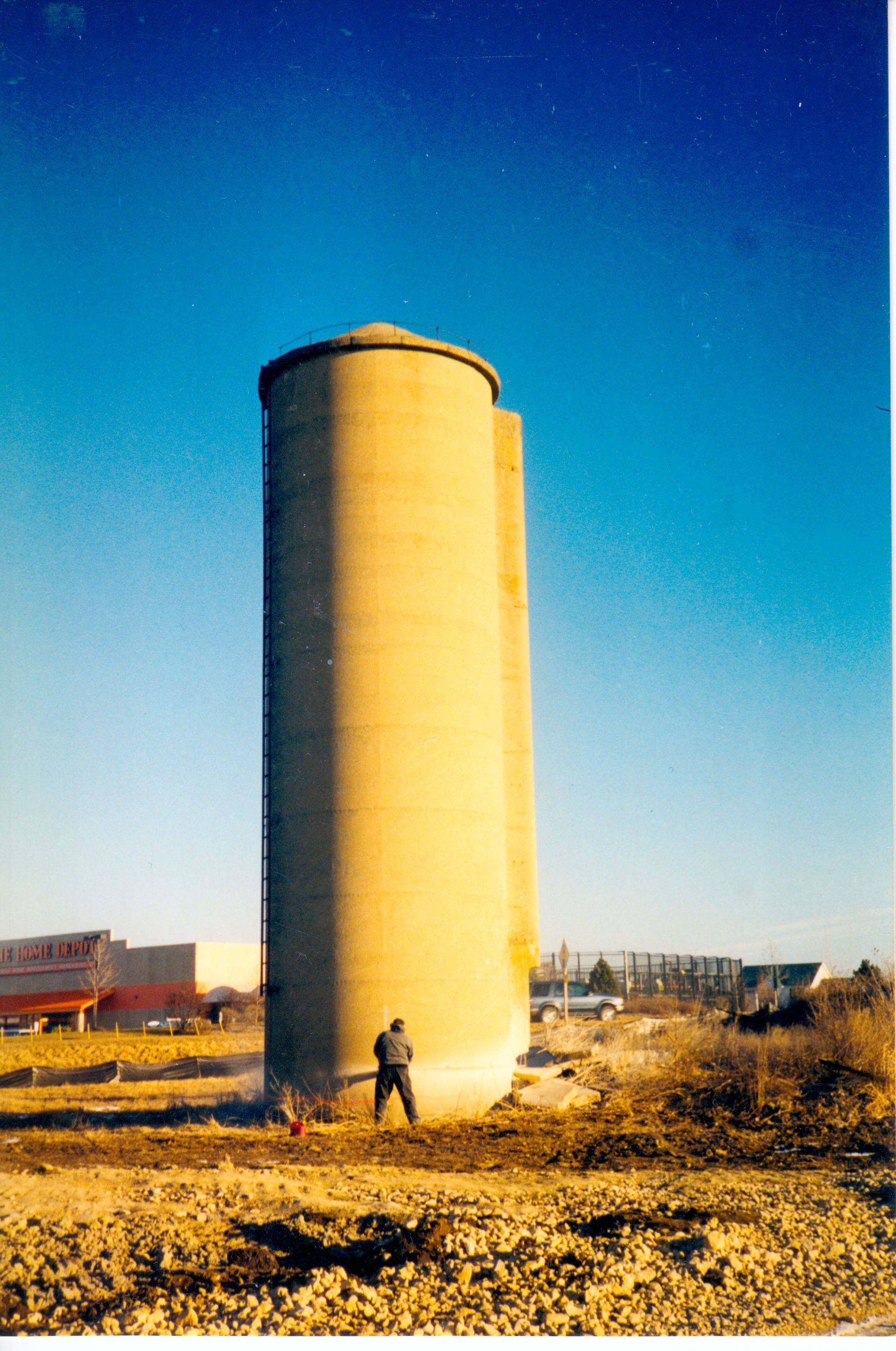 A man is standing in front of a very tall silo