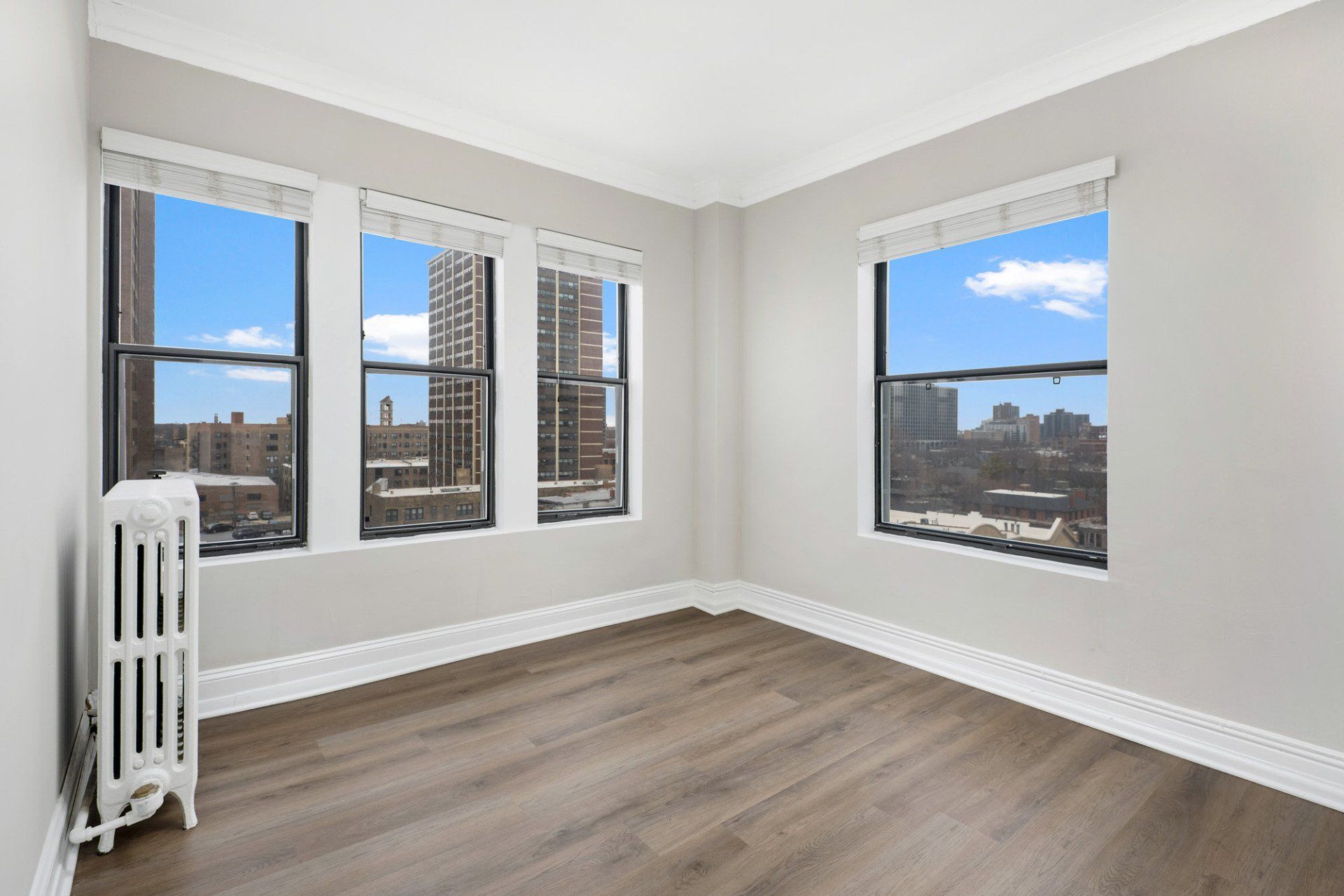 An empty room with a radiator and three windows at Reside on Clarendon.