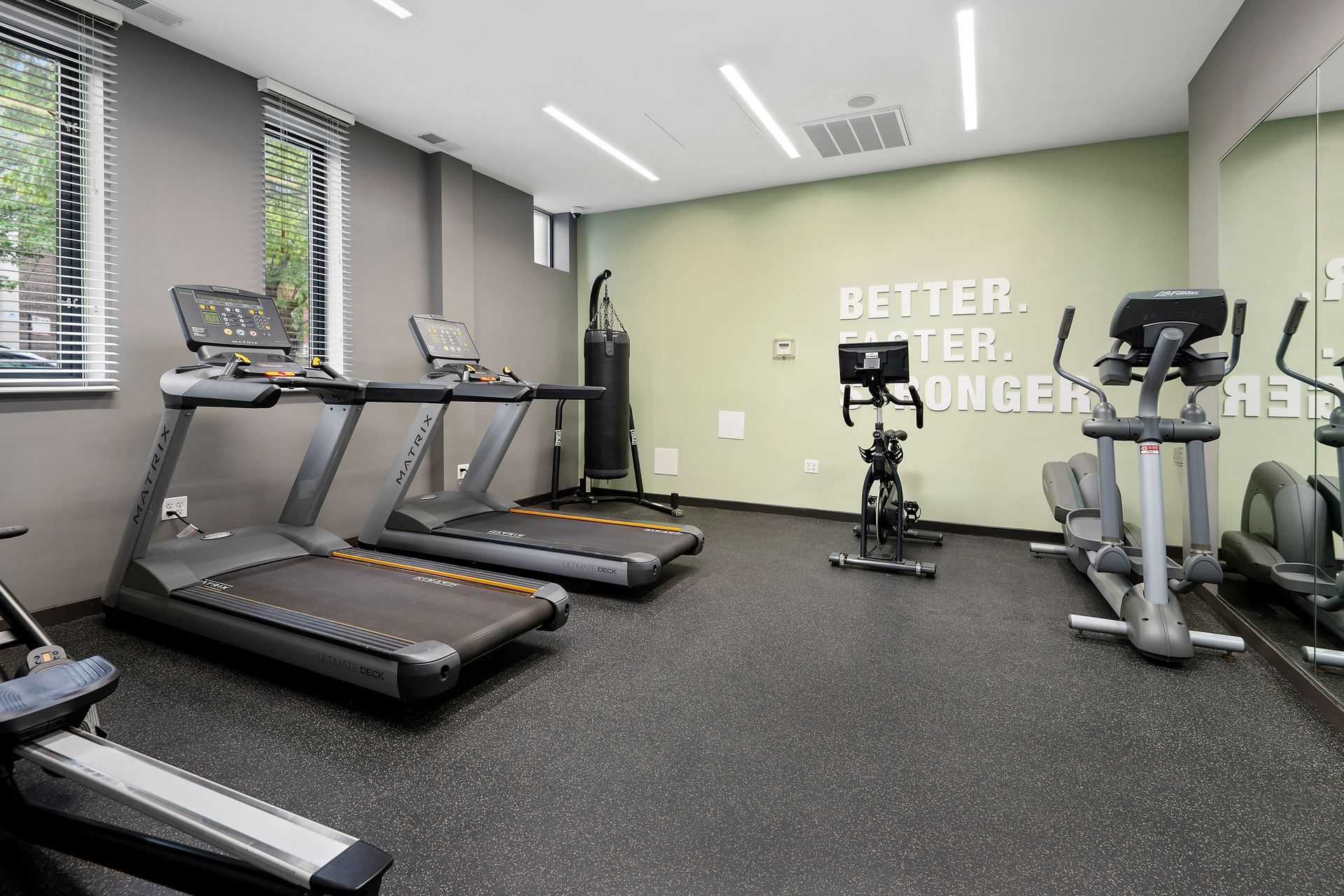 A gym with treadmills , exercise bikes , and a wall that says better at Reside on Clarendon.