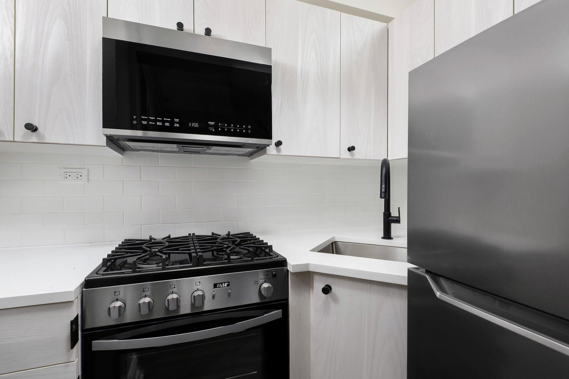 A kitchen with a stove , refrigerator , sink and microwave at Reside on Clarendon.