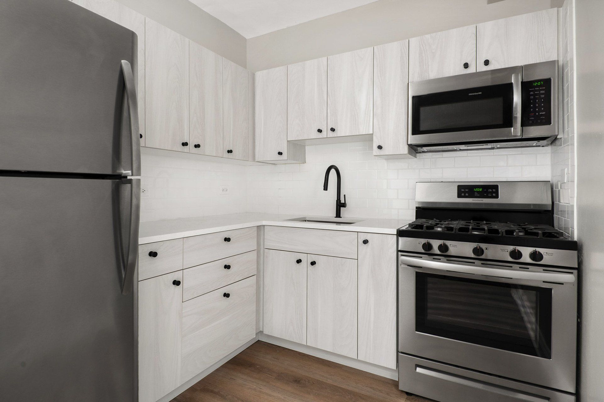 A kitchen with stainless steel appliances and white cabinets at Reside on Clarendon.