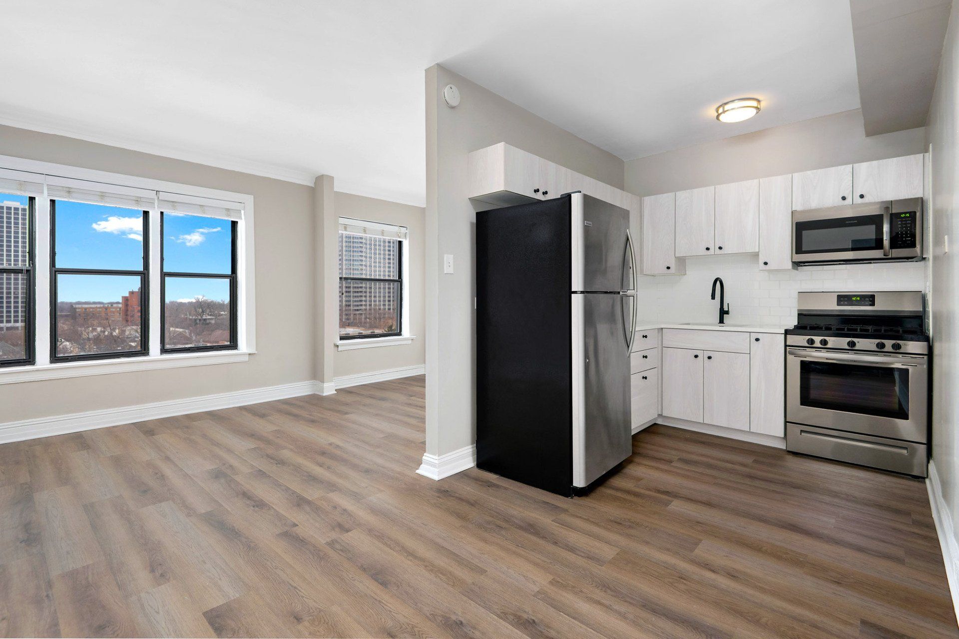 A kitchen with stainless steel appliances and a black refrigerator at Reside on Clarendon.