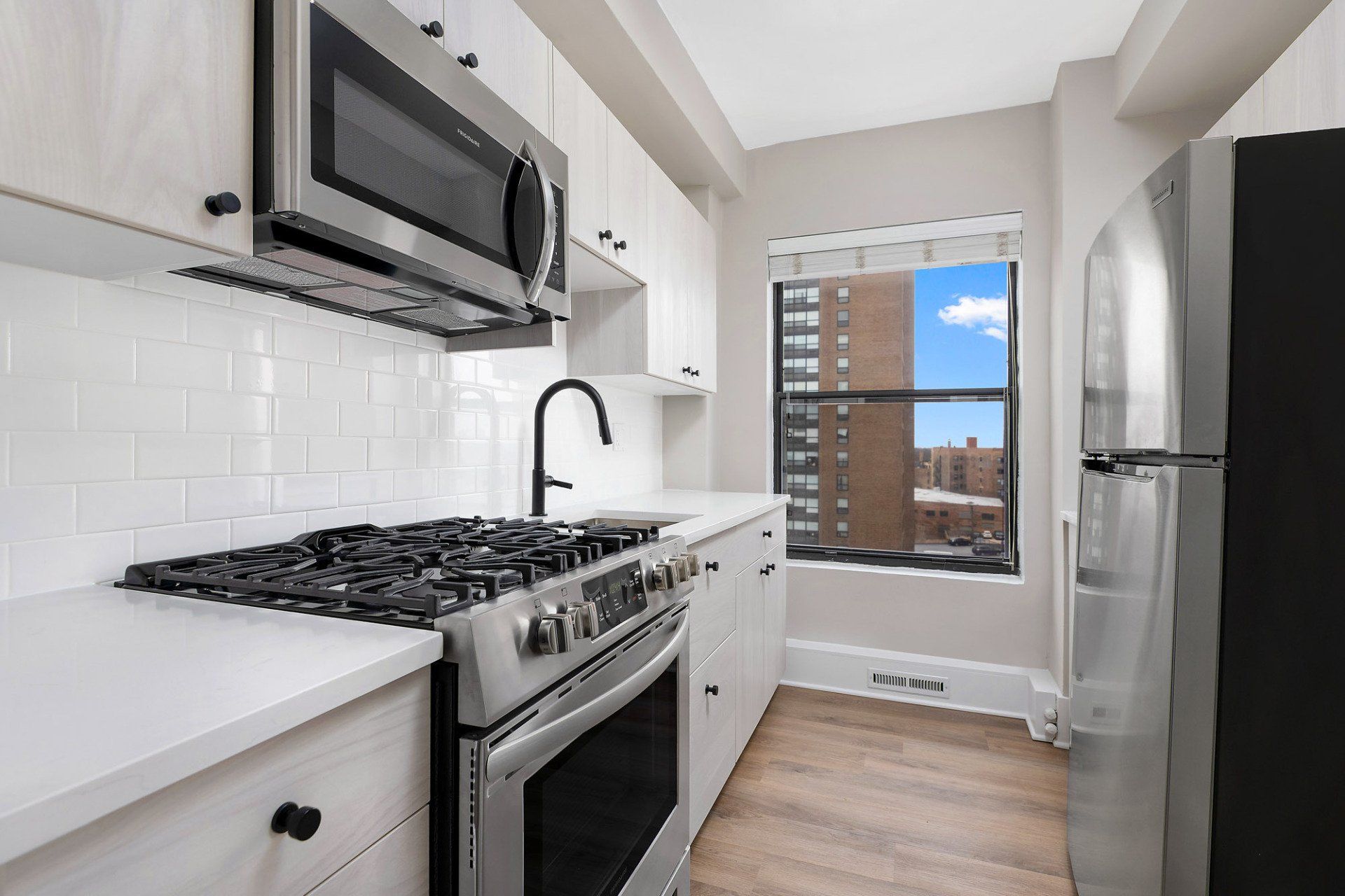 A kitchen with stainless steel appliances and white cabinets at Reside on Clarendon.