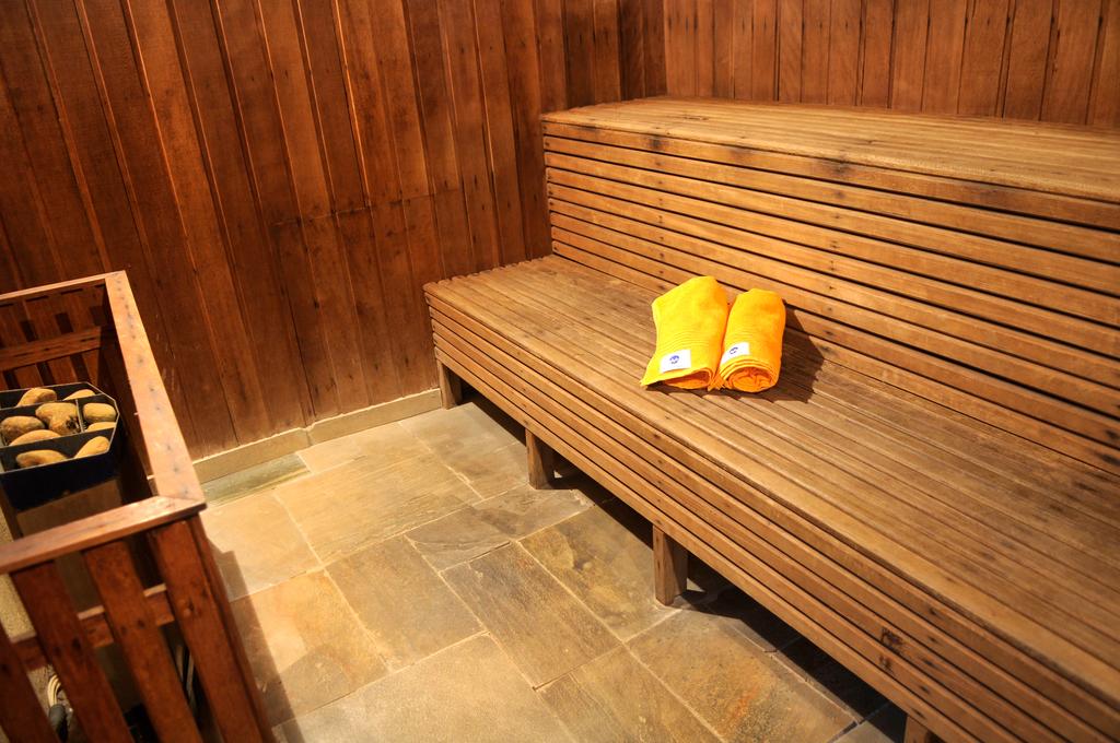 Um par de toalhas amarelas estão sobre um banco de madeira em uma sauna.
