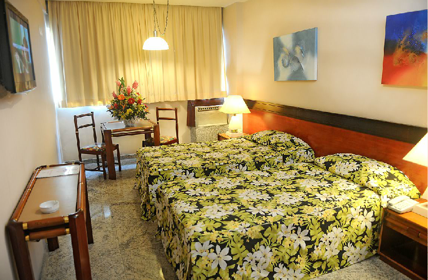 Um quarto de hotel com duas camas, uma mesa e cadeiras