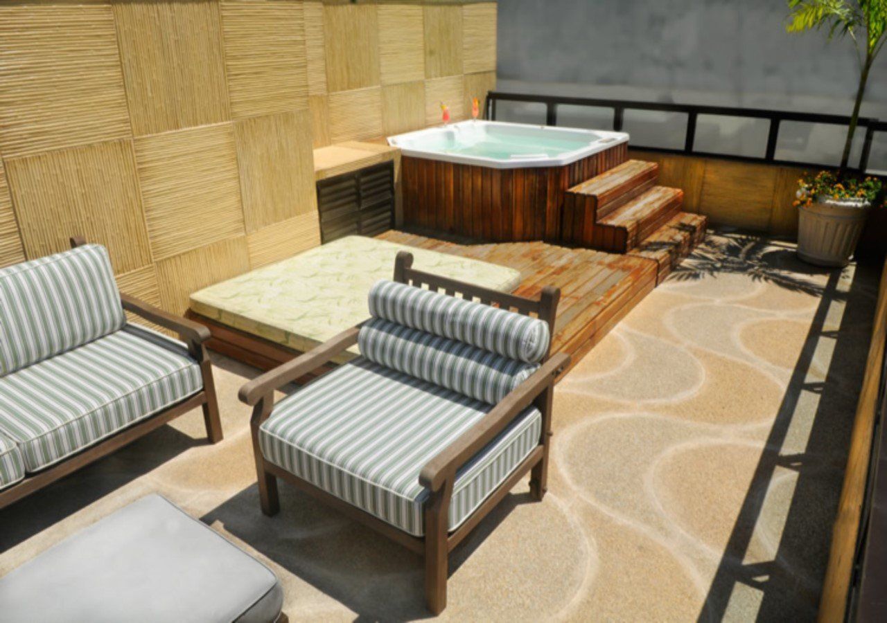 Um pátio com um sofá e cadeiras e uma banheira de hidromassagem