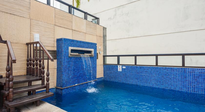 Uma grande piscina com cascata e escadas que levam até ela.