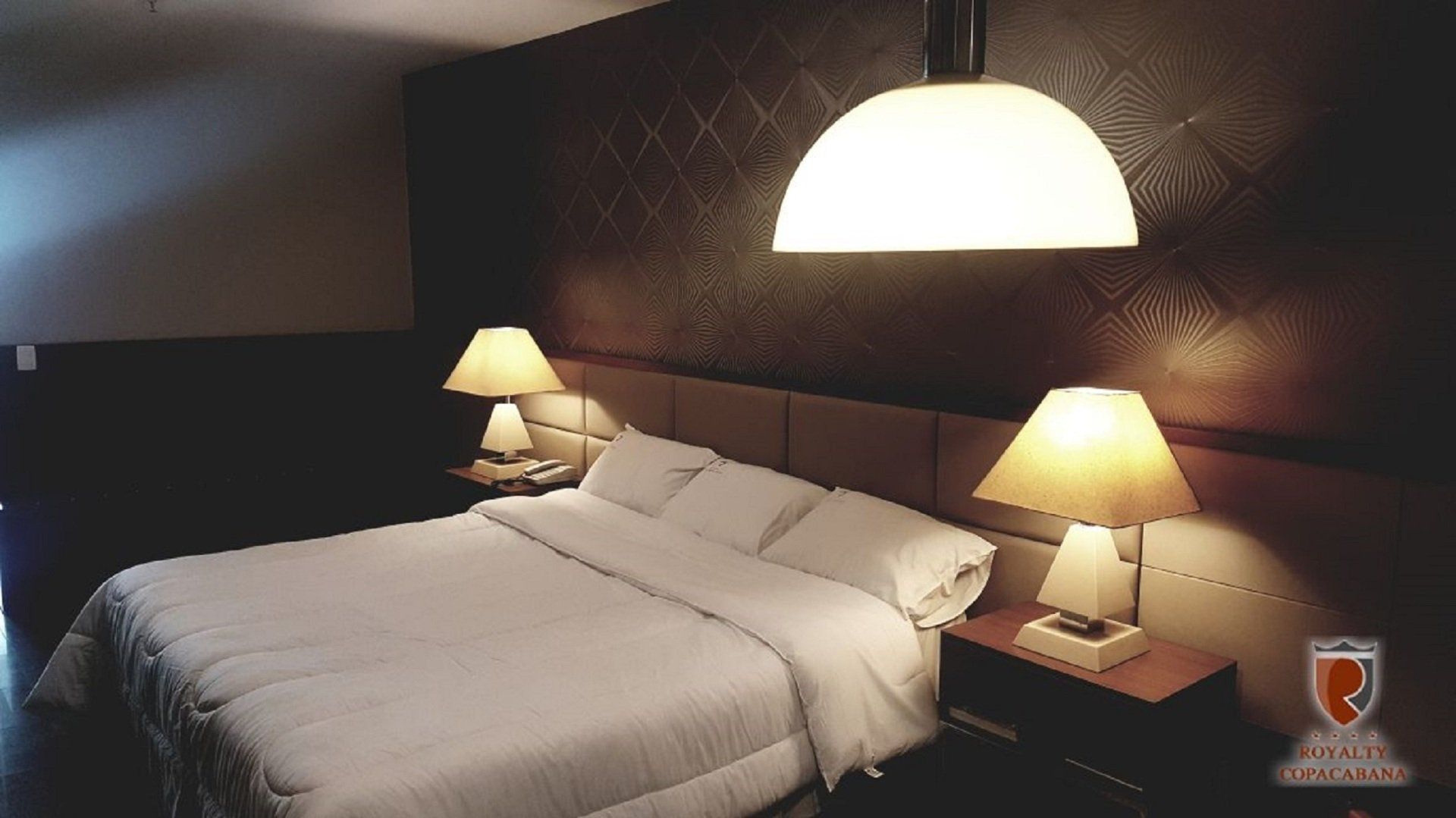 Um quarto de hotel com uma cama e duas lâmpadas