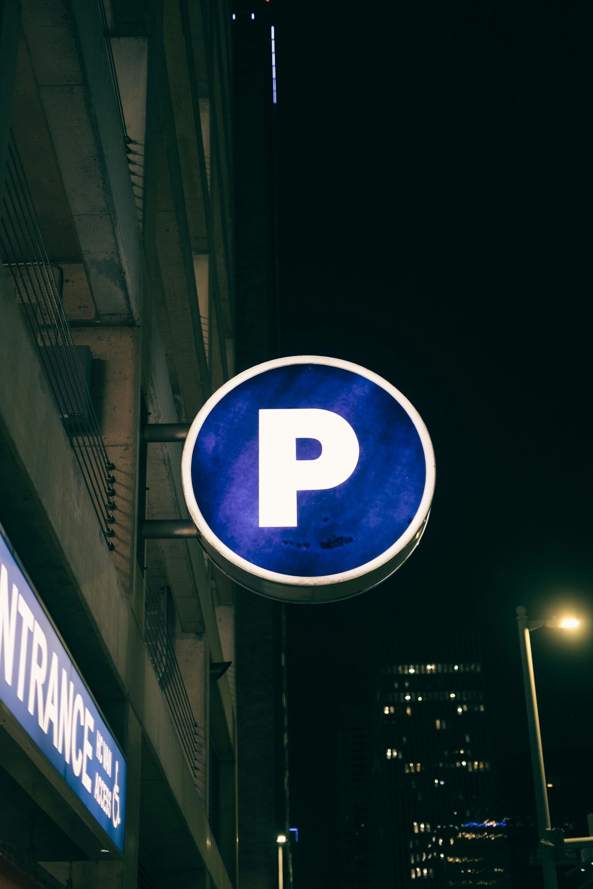 Parking sign at night; blue circle with white 