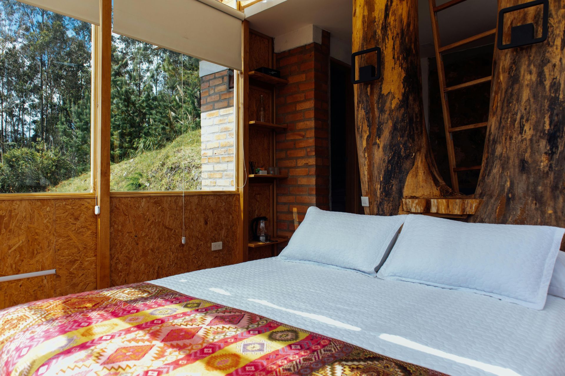 Bedroom with a large bed, natural wood accents, and a window with a view of trees.
