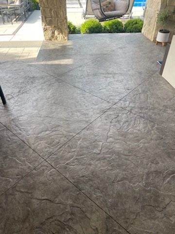 A patio with a concrete floor and a swing in the background.