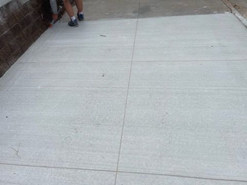 A person is walking on a concrete sidewalk next to a brick wall.