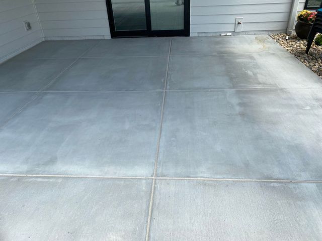 A concrete floor with a sliding glass door in the background