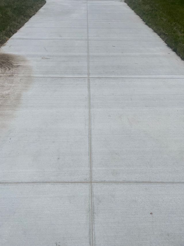 A concrete driveway with grass on the side of it.