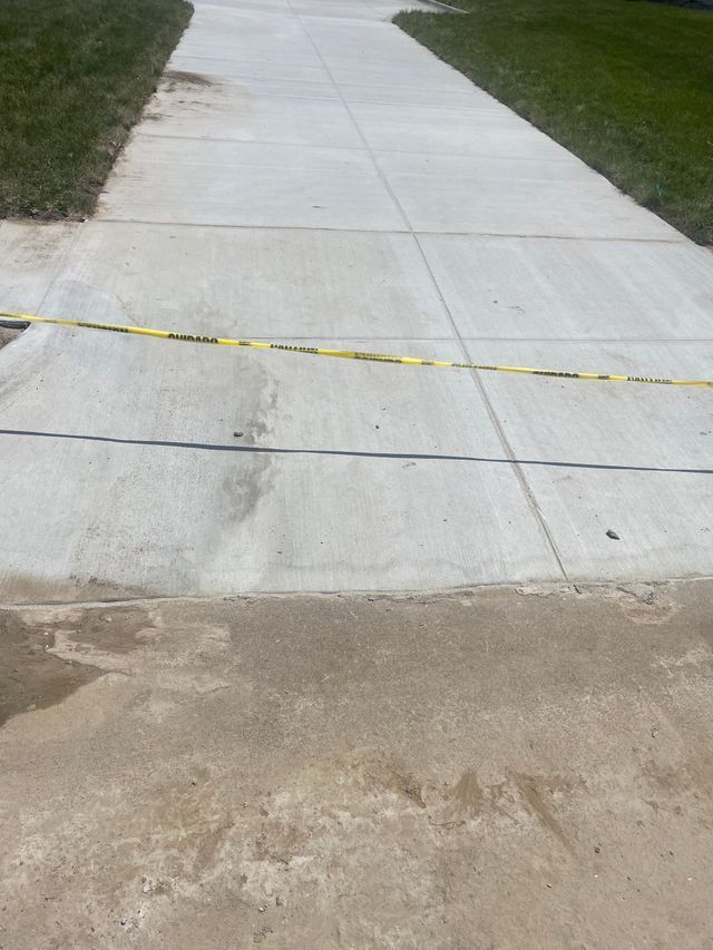 A concrete driveway with a yellow tape on the side of it.