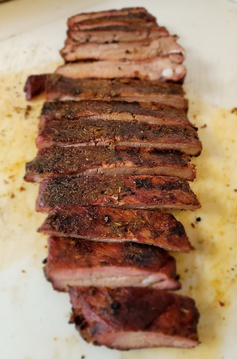 A close up of a sliced pork ribs on a white plate.