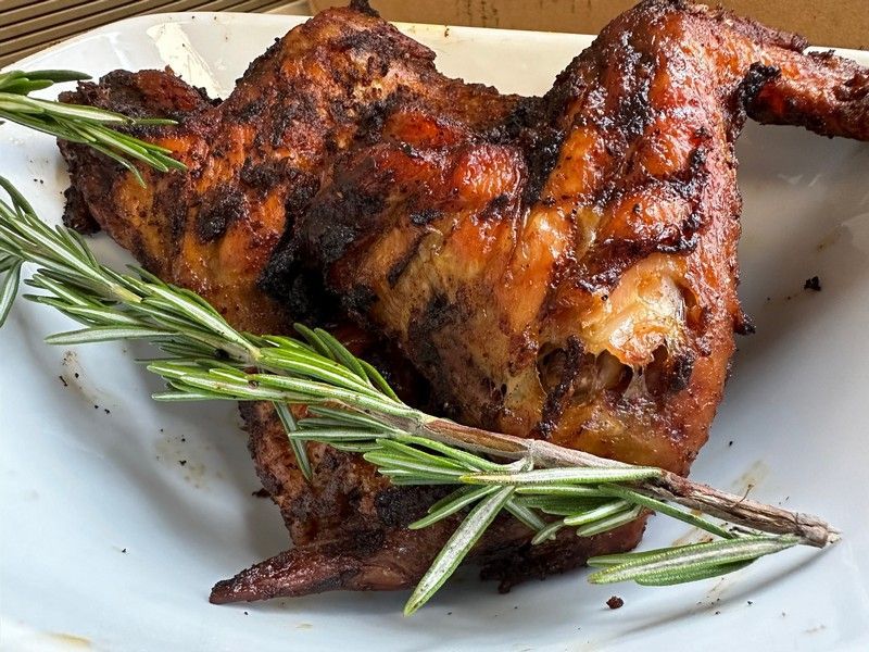 A white plate topped with chicken wings and rosemary