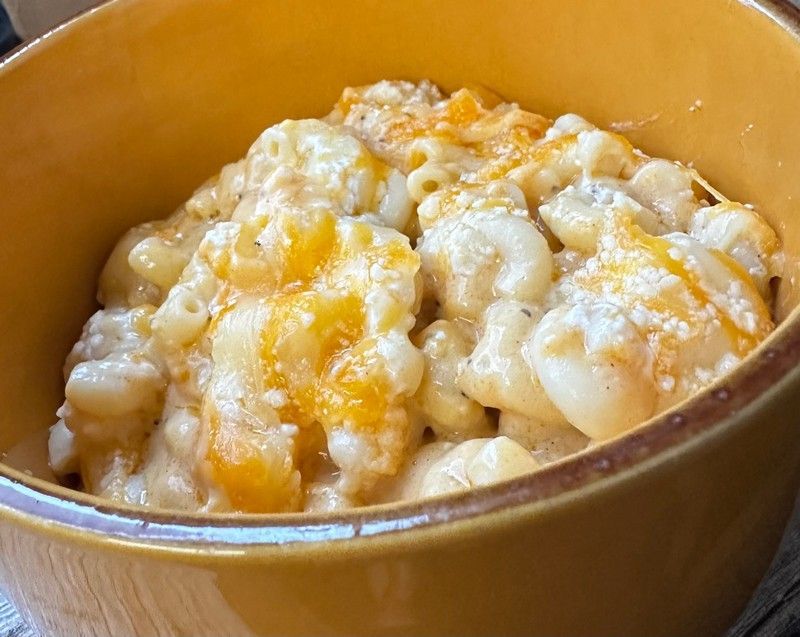A close up of a bowl of macaroni and cheese on a table.