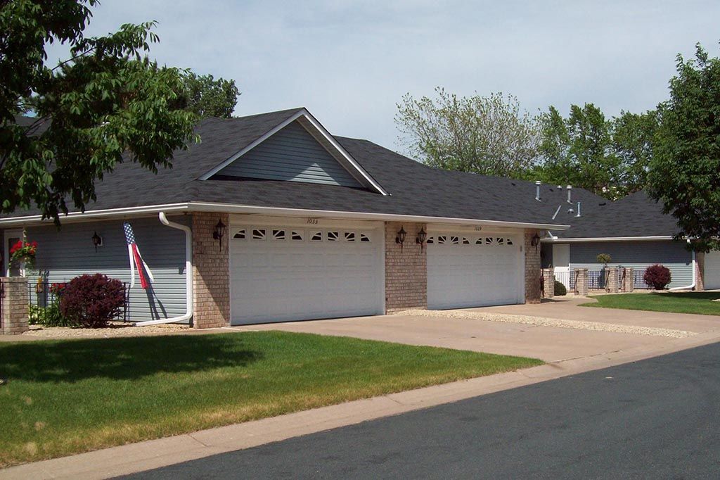 A house with three garage doors has a flag in front of it