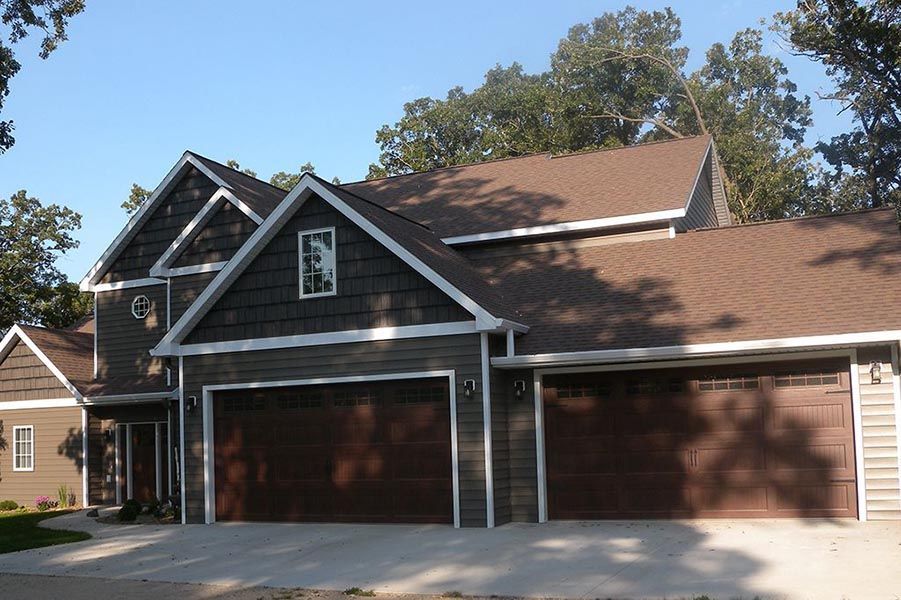 A large house with three garage doors and a brown roof
