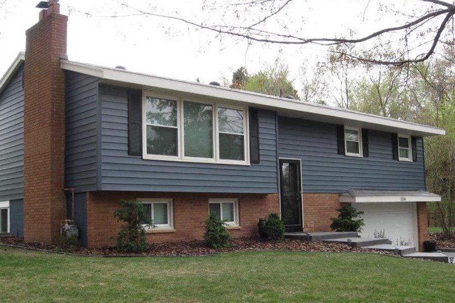 A brick house with a blue siding and black shutters