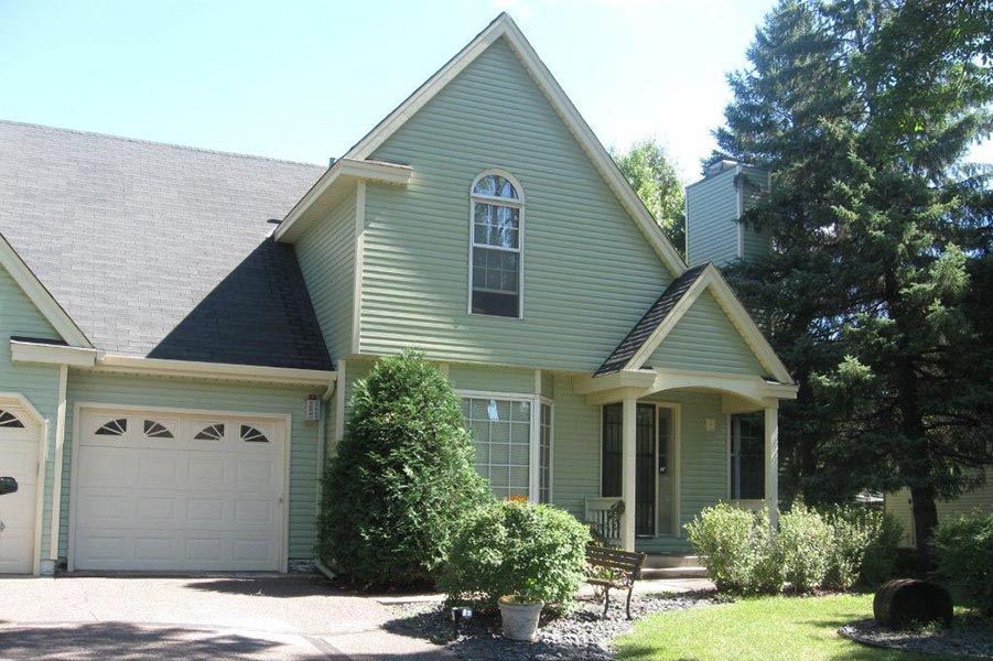 A green house with a white garage door