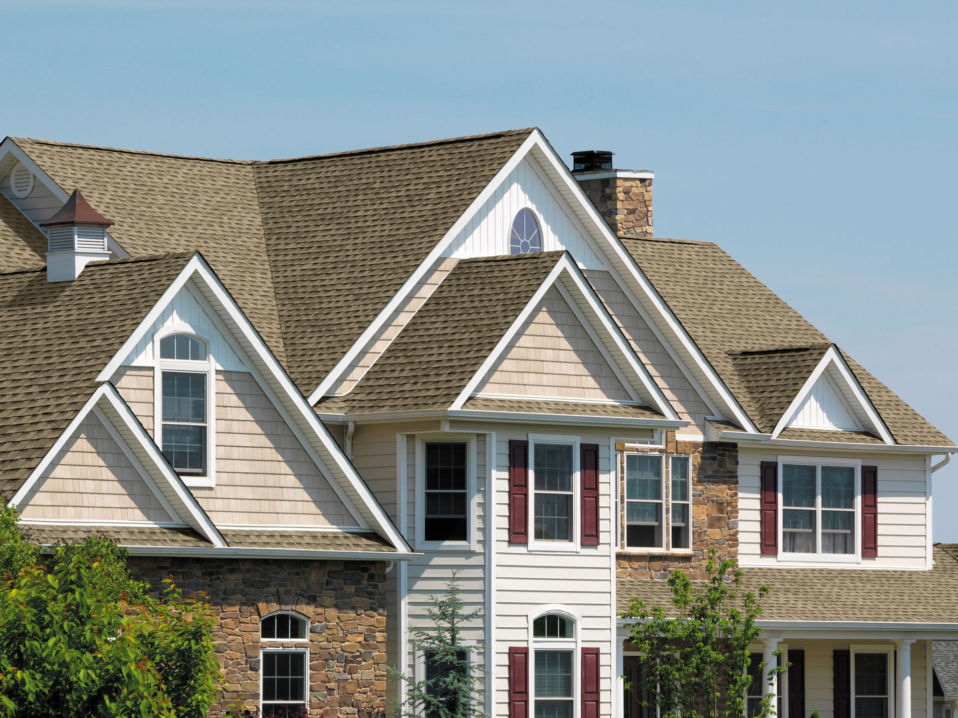 A large white house with a brown roof and red shutters