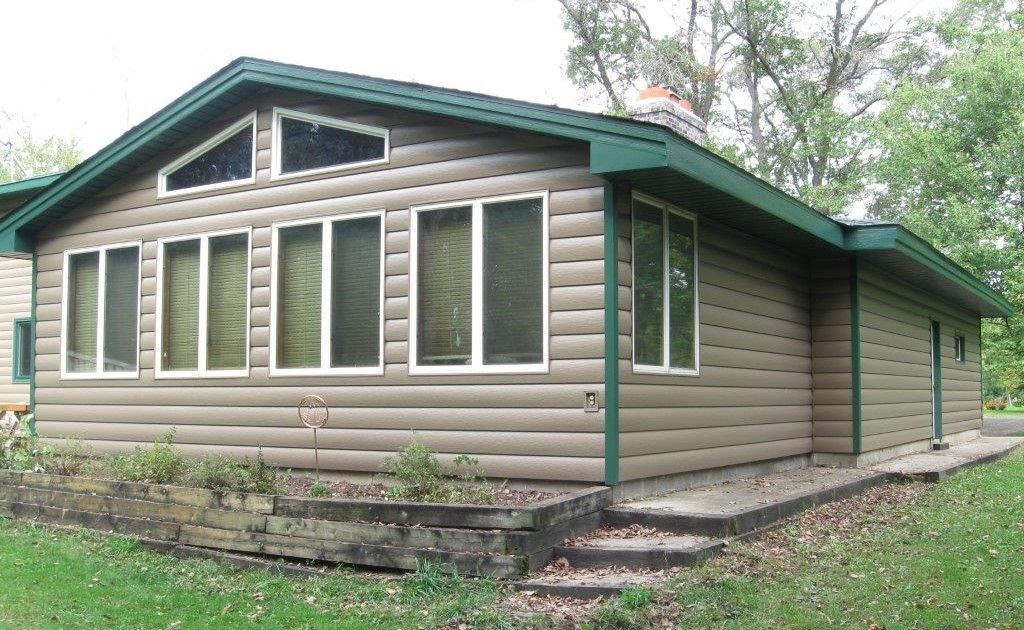 A log cabin with a green roof and lots of windows