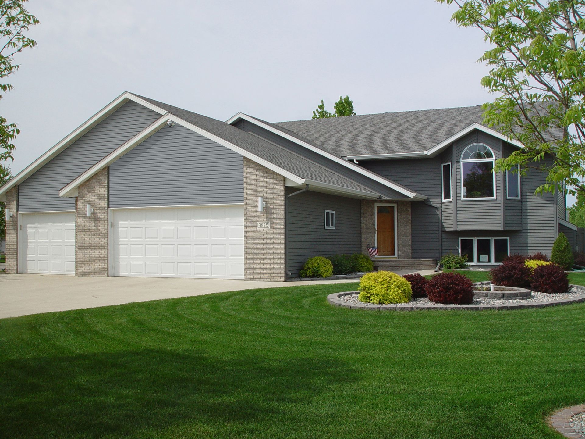 A house with a gray siding and white garage doors