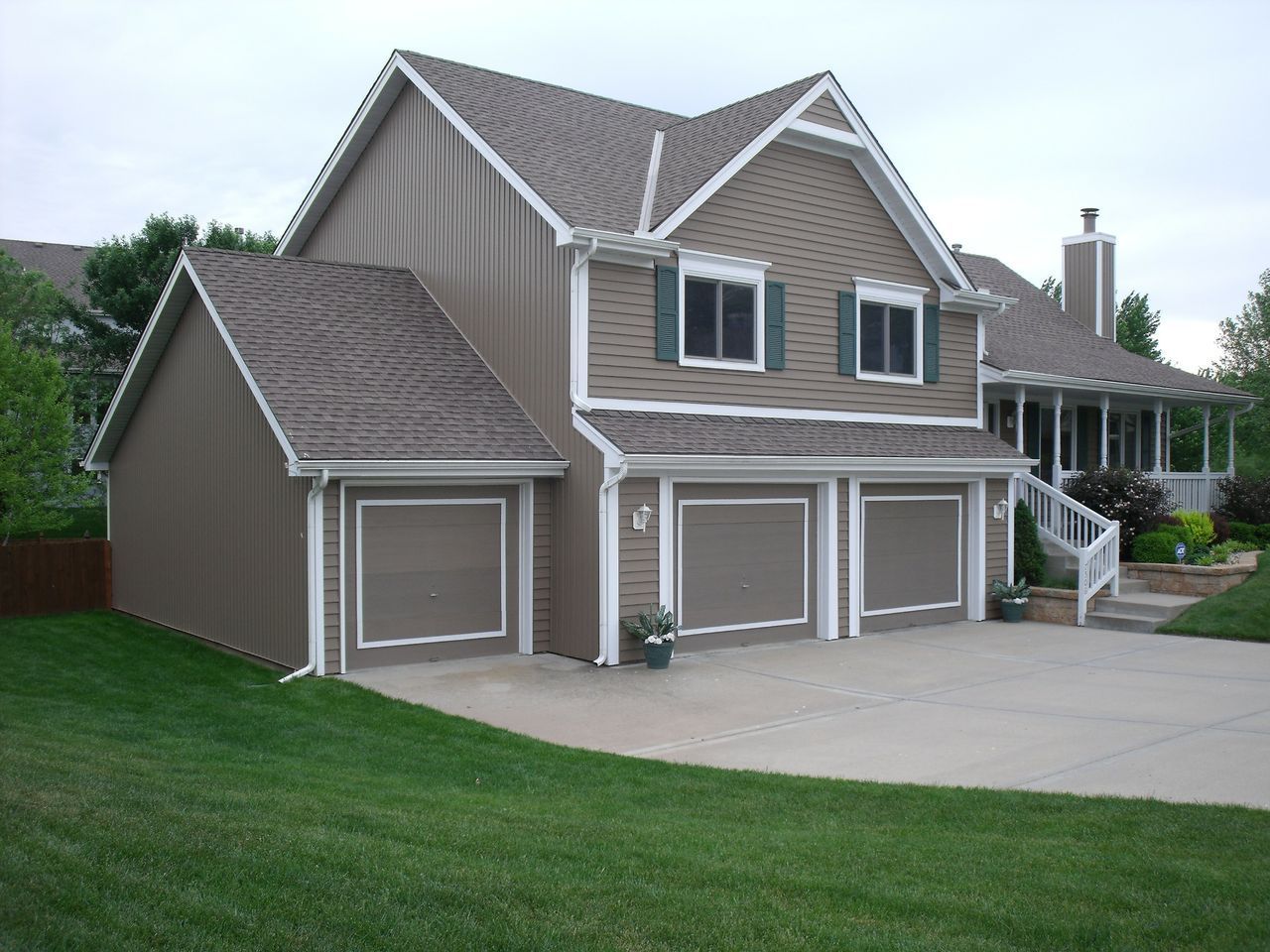 A large house with three garage doors and a porch