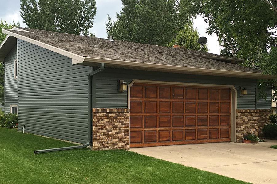 A garage with a wooden garage door and a brick wall.
