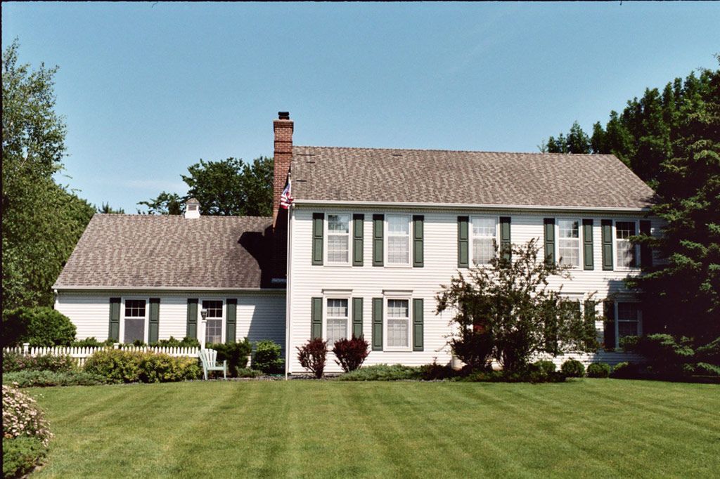 A large white house with a brown roof and a flag on top