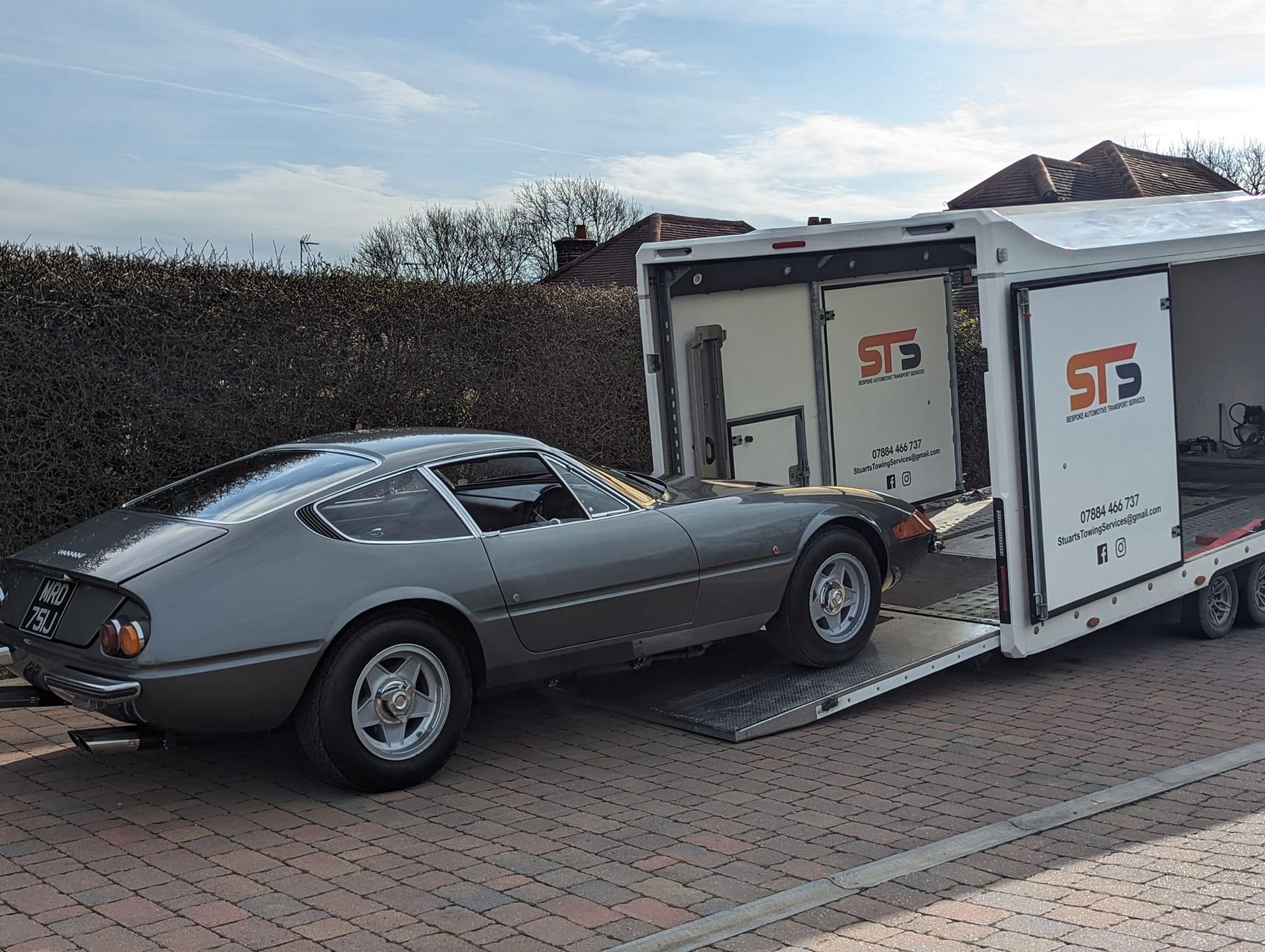 Gray classic car being loaded into a car hauler.
