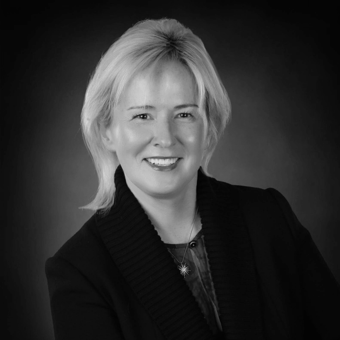 A black and white photo of a woman in a suit smiling.