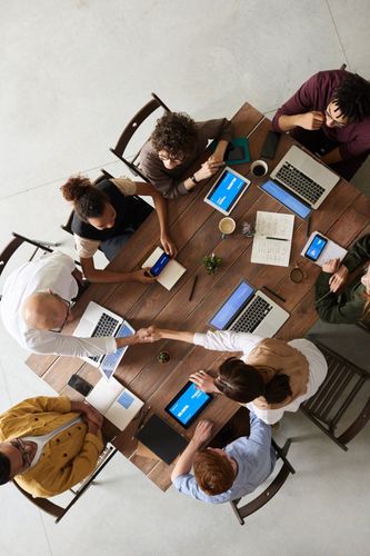 A group of people are sitting around a table shaking hands.