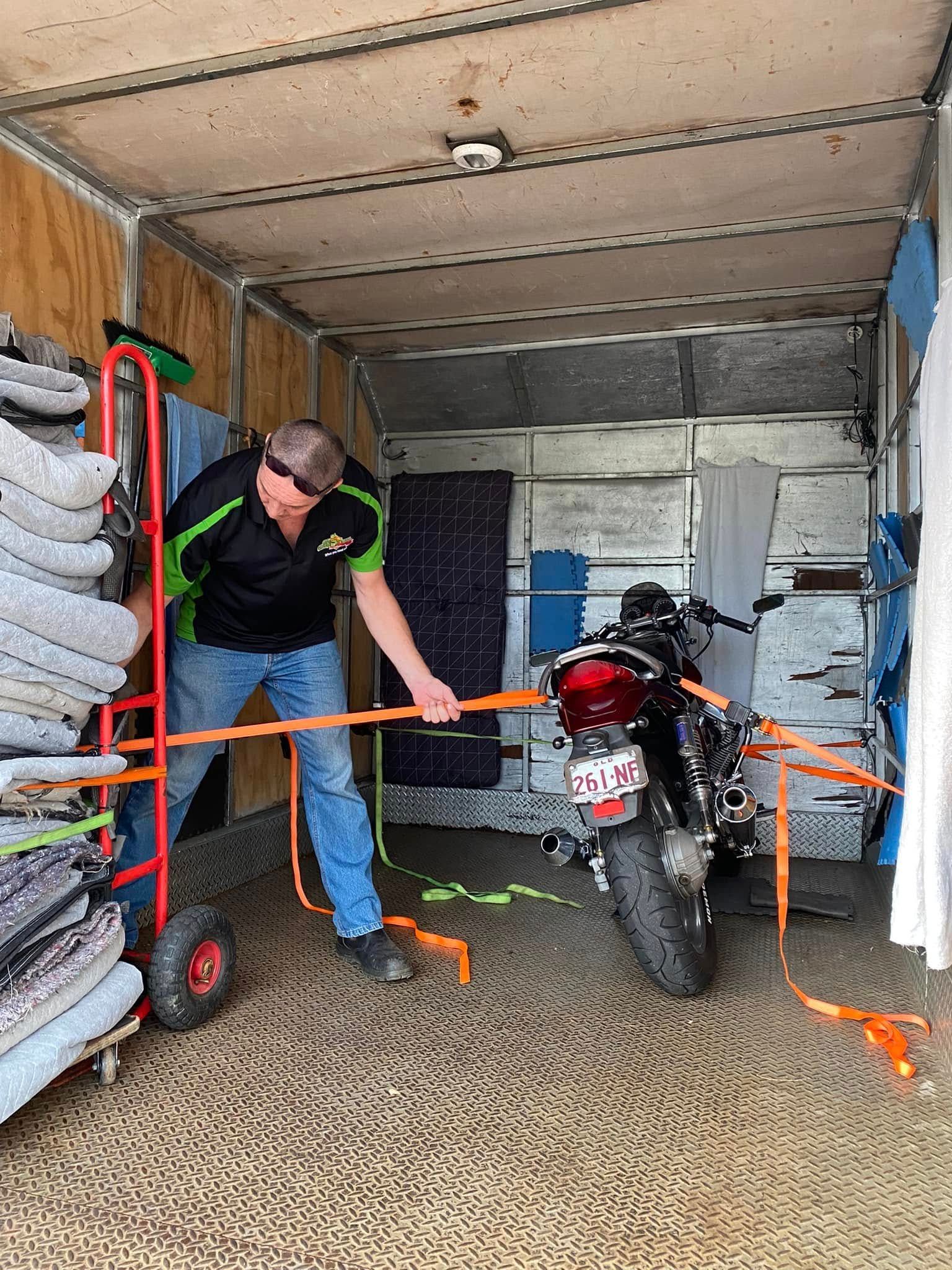 Man Securing a Motorcycle Inside a Moving Truck With Straps — Little Green Truck Bundaberg In Tiaro, QLD