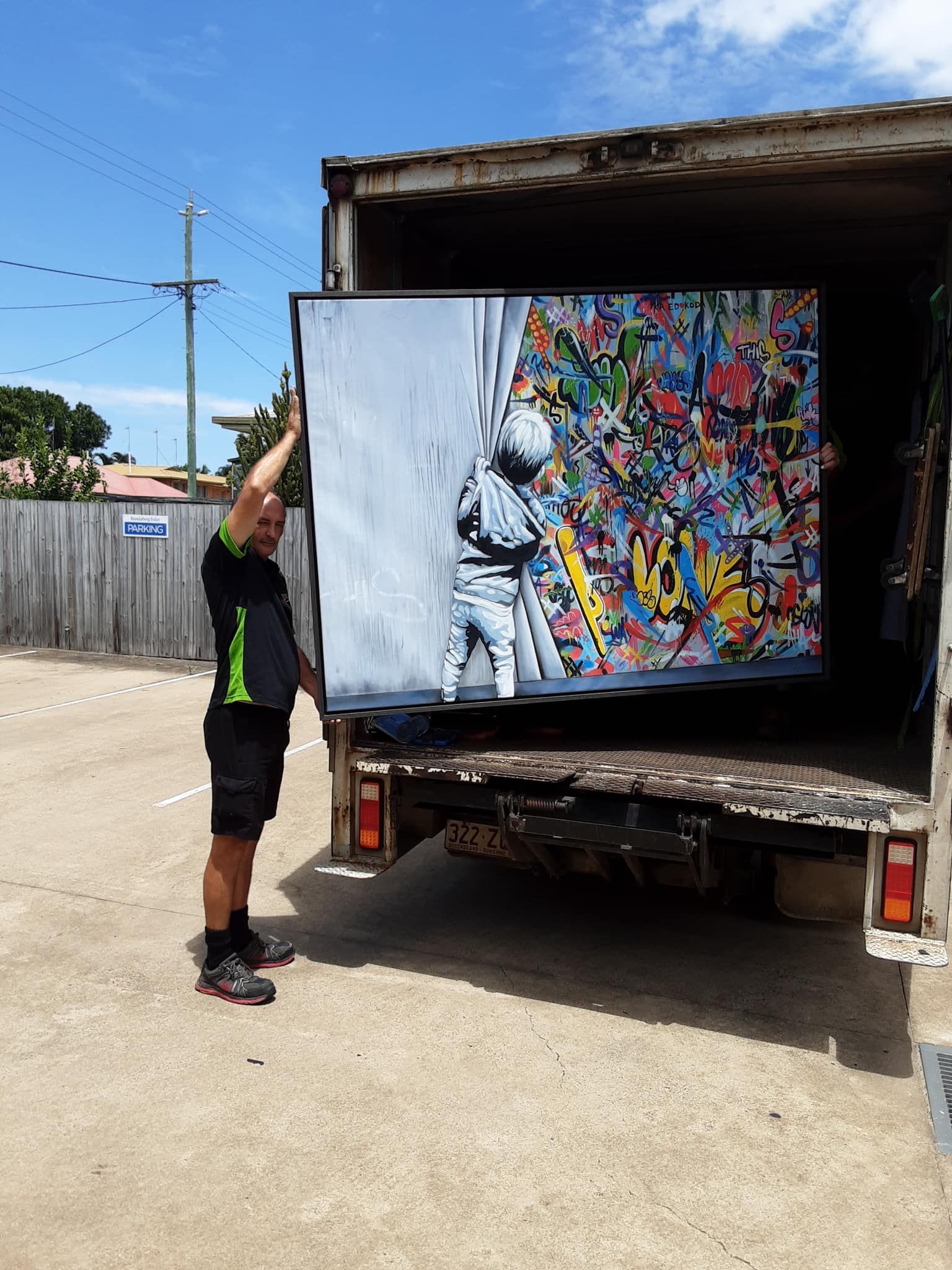 Man Holding a Large Artwork Exiting a Truck — Little Green Truck Bundaberg In Childers, QLD