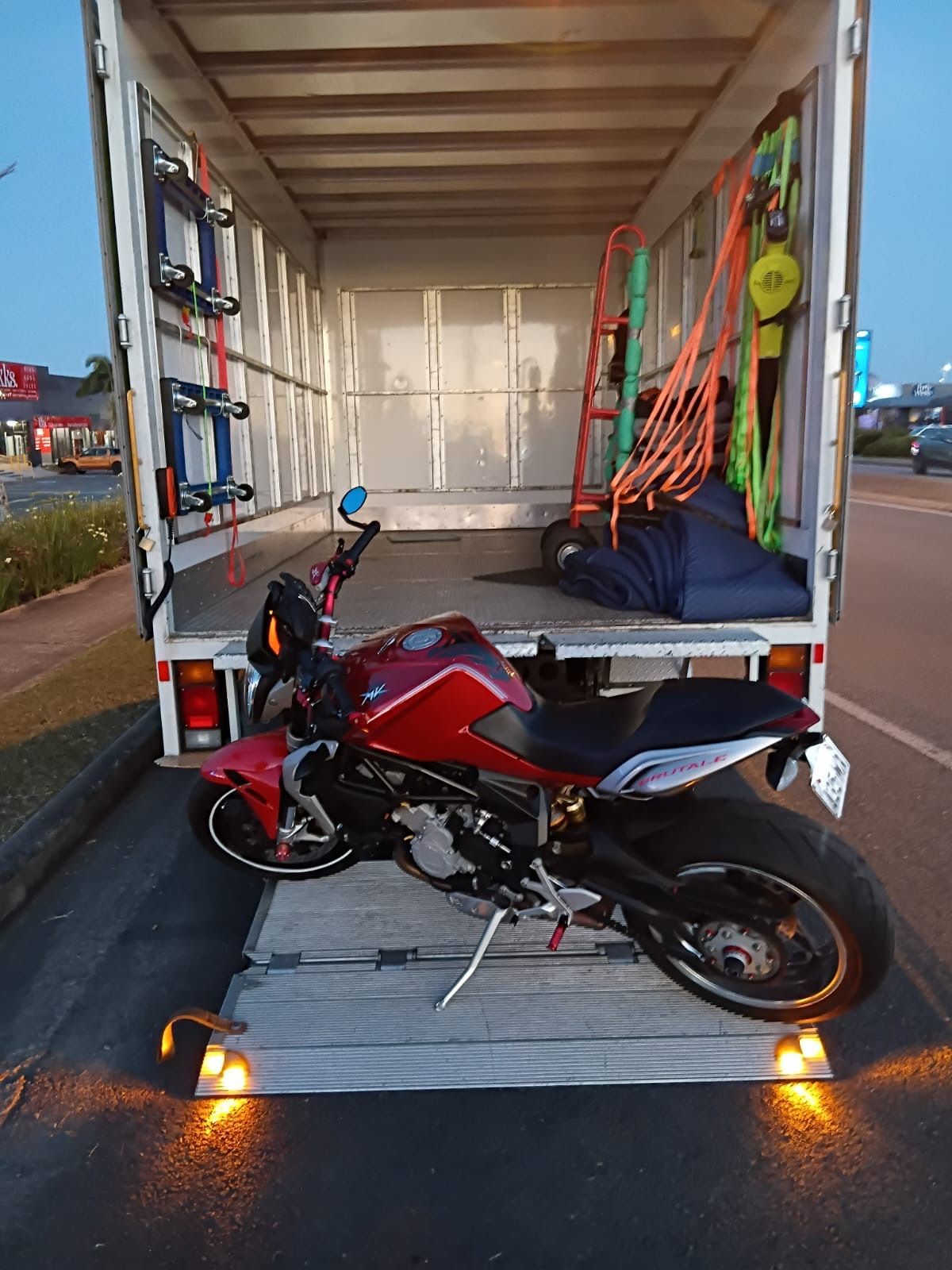 Red motorcycle inside a white truck, likely being transported. Tail lights are lit.  — Little Green Truck Bundaberg In Bundaberg, QLD