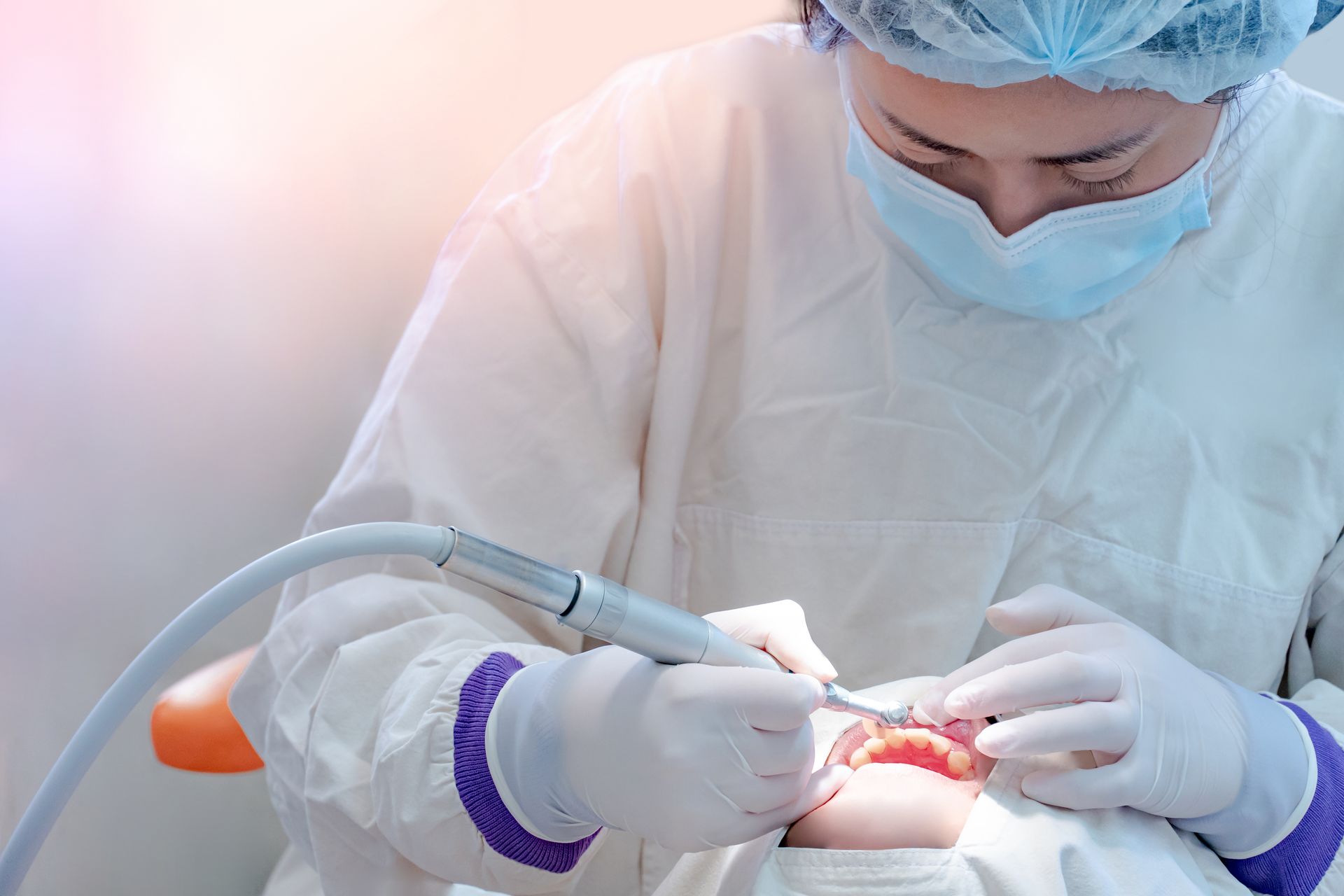 A dental professional performing teeth cleaning with an ultrasonic tool on a patient in a clinic 