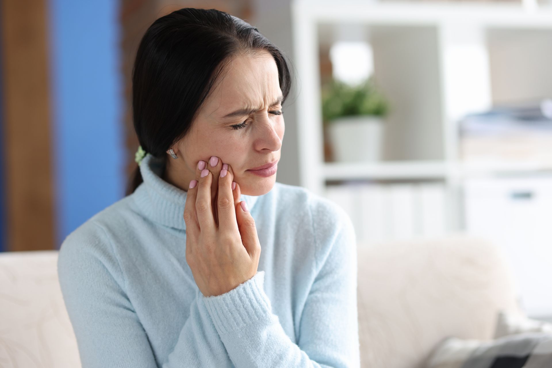 Woman experiencing severe toothache and holding her jaw in pain